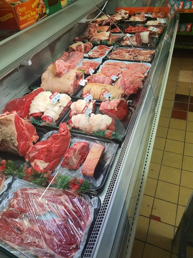 Meat counter displaying fresh beef joints, steaks, bacon, and pork cuts